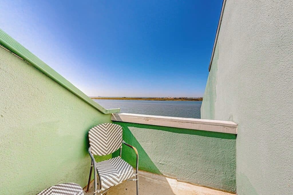 Un balcon donnant sur une étendue d’eau, avec une chaise et une petite table.