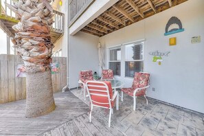 A covered patio with a wooden ceiling, a table with chairs, and a decorative wall with shark-themed artwork. - Cabana Street Unit B (Corpus Christi)