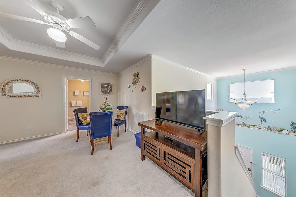 A living room with a television, seating, and a ceiling fan.