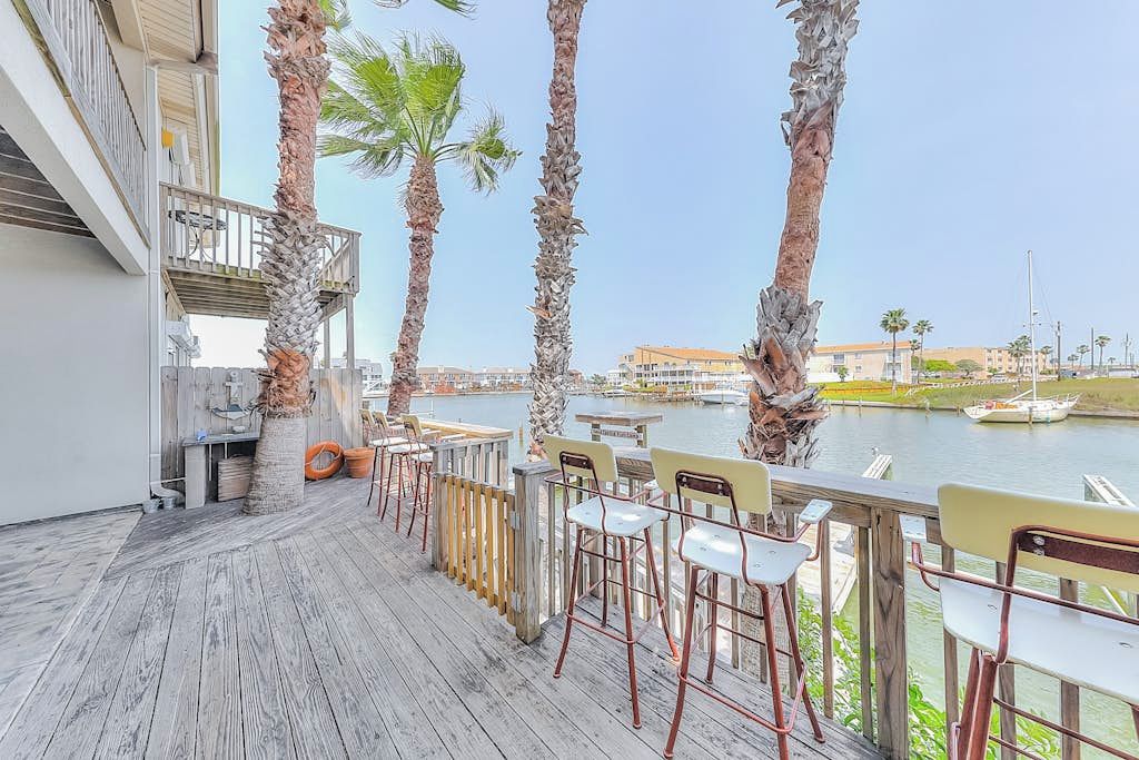 A deck with chairs and tables overlooking a marina with boats.