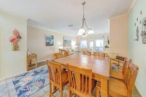 A dining area with a wooden table and chairs, a chandelier, and artwork on the walls. - Cabana Street Unit B (Corpus Christi)
