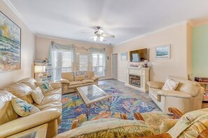 A living room with a beige sofa set, a glass coffee table, and a fireplace. - Cabana Street Unit B (Corpus Christi)