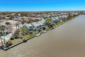 Een woongebied aan het water, met huizen langs een kanaal, voorzien van balkons en wat groen.