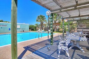 Una piscina con lettini e una zona patio coperta.