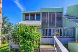 A two-story building with a balcony and a wooden deck. - Puente Vista 119 - Waterfront, Bay Views & Pool (Corpus Christi)