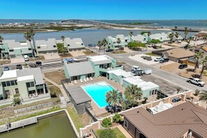 A coastal residential area with a swimming pool, a dock, and a view of the ocean. - Puente Vista 119 - Waterfront, Bay Views & Pool (Corpus Christi)
