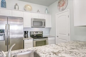 A kitchen with white cabinets, stainless steel appliances, and a granite countertop. - Nemo Cay - Mermaids Splash (Corpus Christi)