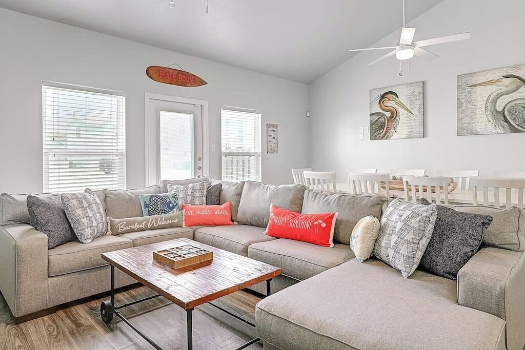 A living room with a sectional sofa, a coffee table, and artwork on the walls.