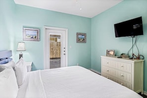 Ein Schlafzimmer mit einem Bett, einer Kommode, einem Fernseher und zwei gerahmten Bildern an der Wand.
