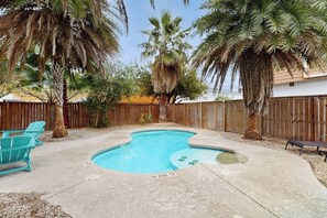 A backyard with a swimming pool, surrounded by palm trees and a wooden fence. - Surf Inn - Under New Ownership (Port Aransas)