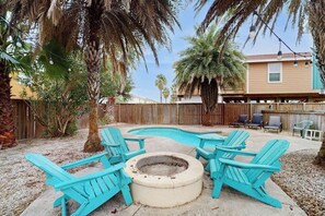 Un jardin avec une piscine, un foyer extérieur et du mobilier de jardin.
