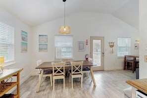 Un comedor con una mesa de madera, cuatro sillas y una lámpara colgante.