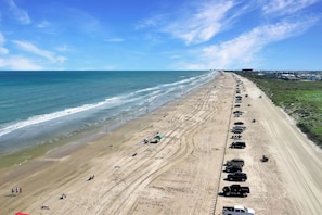 A beach with a row of parked vehicles and a clear view of the ocean. - Surf Inn - Under New Ownership (Port Aransas)
