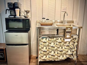 A kitchenette with a microwave, coffee maker, refrigerator, and a sink with a decorative cloth. - King Suite • Clawfoot Tub • Room Only Sardis Lake (Como)