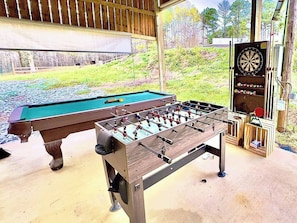 A pool table and a foosball table in a covered area with a dartboard and a small wooden structure. - King Suite • Clawfoot Tub • Room Only Sardis Lake (Como)