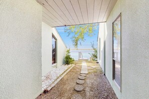 A narrow pathway leading to a building with a view of a body of water. - Puente Vista  120 - Wilson's Watering Hole - Captain’s Quarters (Corpus Christi)