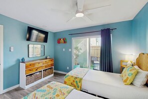 A bedroom with a bed, a dresser, a television, and a window with curtains. - Puente Vista  120 - Wilson's Watering Hole - Captain’s Quarters (Corpus Christi)