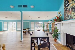 A spacious room with a long dining table, chairs, a fireplace, and a bookshelf. - Puente Vista  120 - Wilson's Watering Hole - Captain’s Quarters (Corpus Christi)