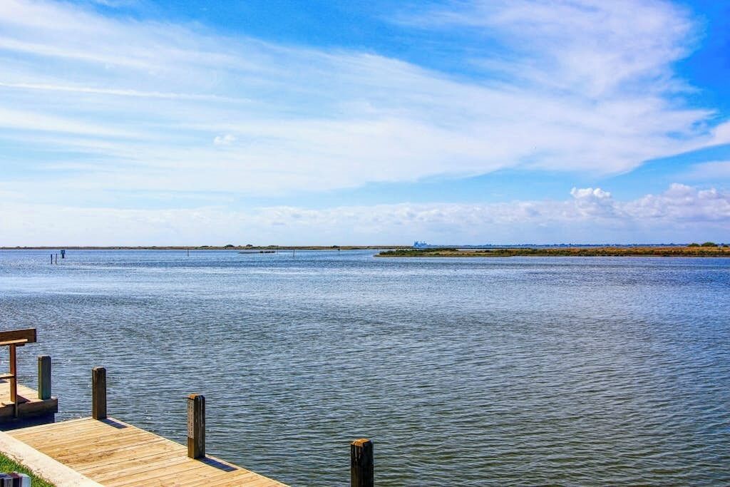 A wooden dock extending into calm water with a clear sky above.