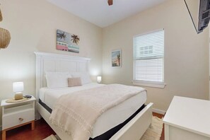 Ein Schlafzimmer mit einem Bett, Nachttischen, einer Fensterbank und Wandbildern.