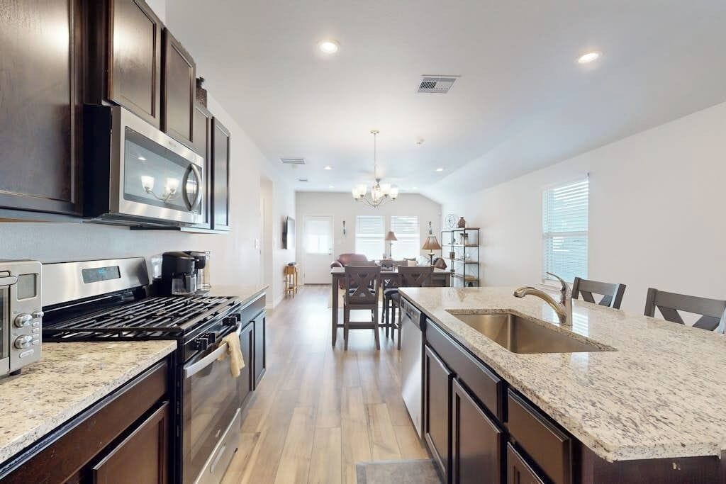 A kitchen with dark cabinetry, a granite countertop, a stainless steel range, and a built-in microwave.