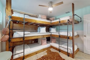 A bunk bed room with a ceiling fan, wooden beams, and a light-colored floor. - Coral Kai - Arcade Games, Close to the Water (Fulton)
