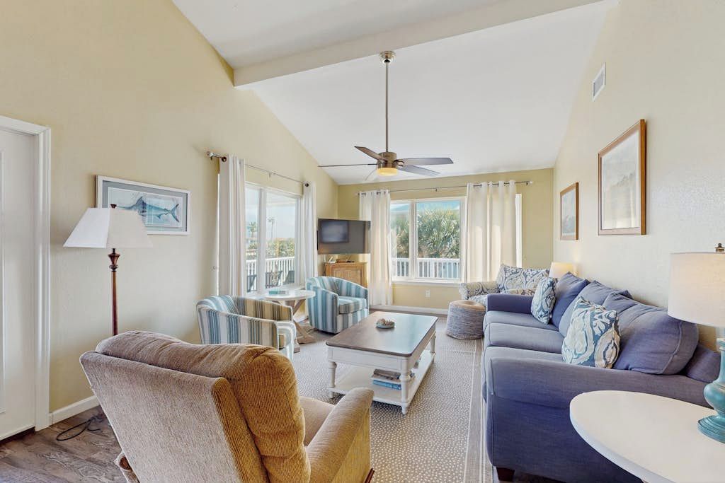 A spacious living room with a ceiling fan, a television, and a large window with curtains.