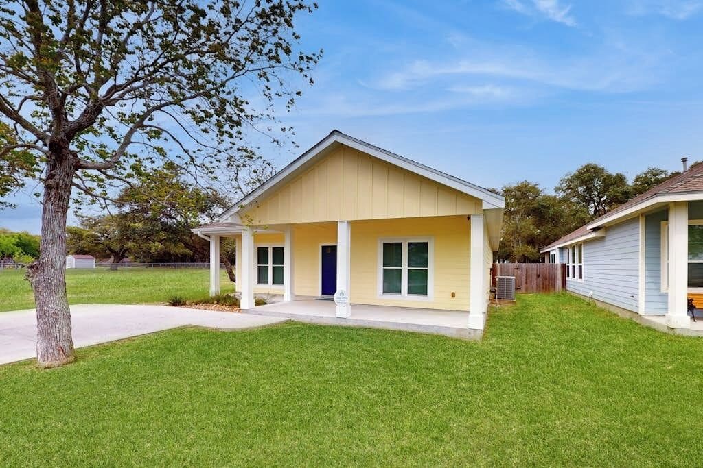 A single-story residential house with a front porch, a visible garage door, and a well-maintained lawn.