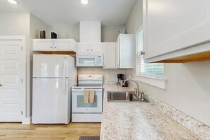 A compact kitchen with white cabinetry, a refrigerator, a microwave, an oven, and a sink. - Kamp ENJoY #157 - Pool, Fishing Pond & Dogs OK (Rockport)