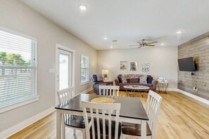 A spacious living area with a dining table, white chairs, a sofa, and a ceiling fan. - Kamp ENJoY #157 - Pool, Fishing Pond & Dogs OK (Rockport)