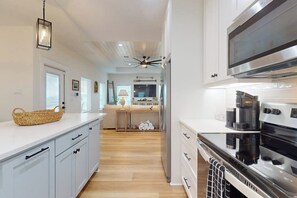A modern kitchen with white cabinetry, a stainless steel range hood, and a wooden floor. - A Sea Es La Vida - Water Views & Outdoor Kitchen (Rockport)