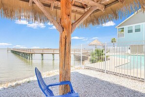 A beachside view with a wooden gazebo, a pool, and a pier extending into the water. - The Surf Rider, Unit 2 (Rockport)