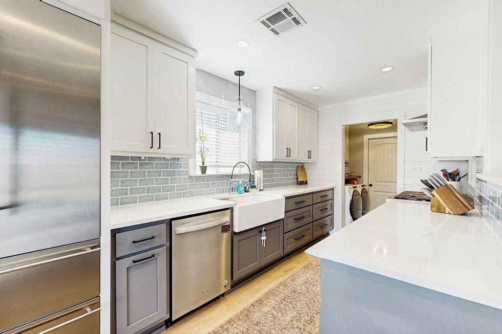 A modern kitchen with stainless steel appliances, white cabinetry, and a large island.