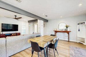 A modern living space with a dining area, a television, and a kitchen counter. - The Bluff Breeze - Canal-Front with Large Yard (Corpus Christi)