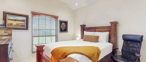 Un dormitorio con una cama, un escritorio, una silla, un ventilador de techo y una ventana con persianas.