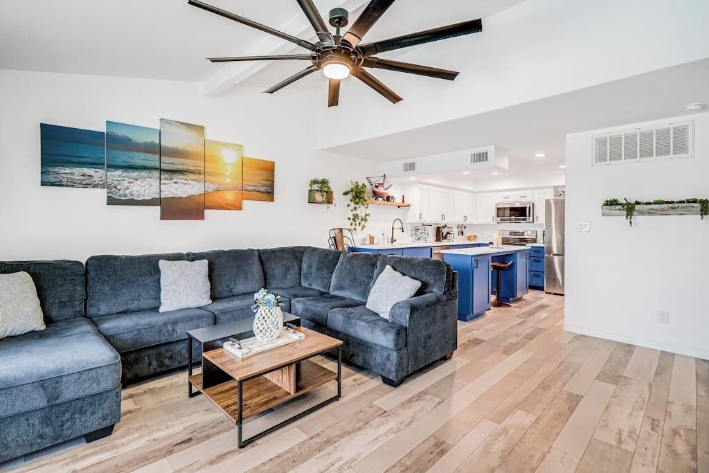 A modern living room with a sectional sofa, a coffee table, and a ceiling fan.