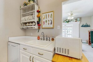A kitchen with white cabinetry, a built-in sink, and a white refrigerator. - Seashell Shack - Cozy Galveston Home, Fenced Yard (Galveston)