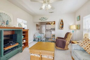 A living room with a television, a dining table, and a sofa. - Seashell Shack - Cozy Galveston Home, Fenced Yard (Galveston)
