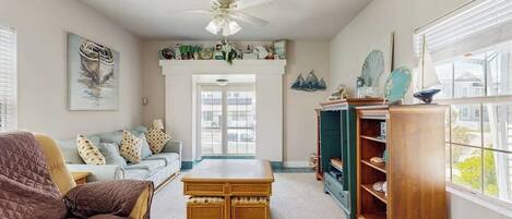 A living room with a sofa, a coffee table, a bookshelf, and a ceiling fan.