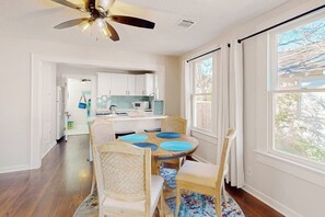 A dining area with a round table, chairs, and a ceiling fan. - Kay's Kottage - Fenced Yard, Near Beach & Seawall (Galveston)