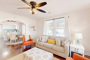 Ein Wohnzimmer mit einer Couch, Sesseln, einem Couchtisch und einem Deckenventilator.