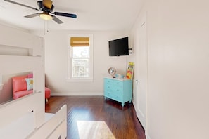 A room with a bed, a dresser, a television, and a window. - Kay's Kottage - Fenced Yard, Near Beach & Seawall (Galveston)