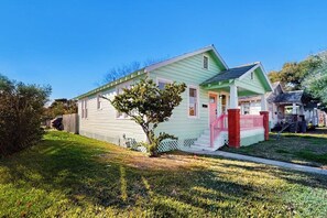 A single-story house with a front porch, a small tree, and a well-maintained lawn. - Kay's Kottage - Fenced Yard, Near Beach & Seawall (Galveston)