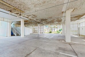 Eine leere Parkgarage mit Betonböden und weißen Säulen, einer Treppe und Blick auf Gebäude im Freien.