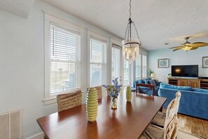 Ein Essbereich mit einem Holztisch und Stühlen, einer Hängelampe und einem blauen Sofa im Hintergrund.