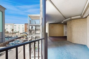 Ein Balkon mit Blick auf einen Parkplatz und Gebäude, ein Müllschachtschild und ein Betonboden.