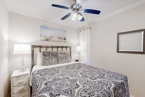 Ein Schlafzimmer mit einem Bett, zwei Nachttischlampen, einem Deckenventilator, einem Bild an der Wand und einem Fenster mit Vorhängen.