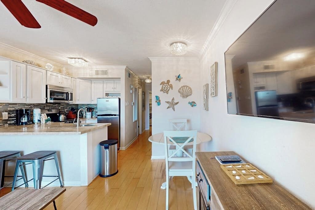 A modern kitchen with white cabinetry, a central island with bar stools, and decorative sea-themed wall art.