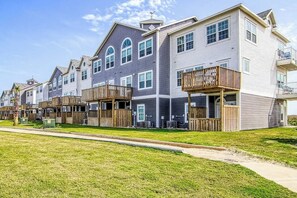 A row of modern multi-story residential buildings with balconies and wooden decks. - Pathway to the Sea 14838 (Corpus Christi)