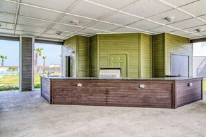 A covered outdoor area with a wooden bench and a green wall. - Pathway to the Sea 14838 (Corpus Christi)